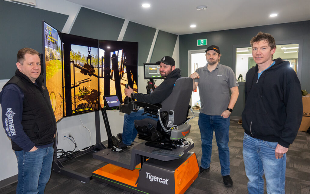 Andy Driedger, owner of Garden River Logging Ltd. (seated) takes the processor simulator through its paces. Philip Unrau, CEO of FTEN Group of Companies at left, along with Gregor Scott from the Tigercat electronic systems group, and forestry consultant, Jon Goertzen at right.
