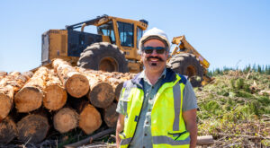 Portrait of a Tigercat customer with logs and a machine in the background